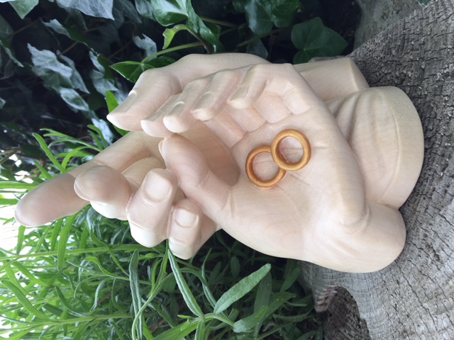 Geborgenheit der Ehe, geschnitzte Hände mit Ringen aus Holz